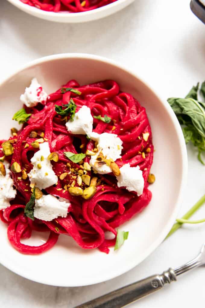 Bright pink pasta made with beet sauce in a white bowl.
