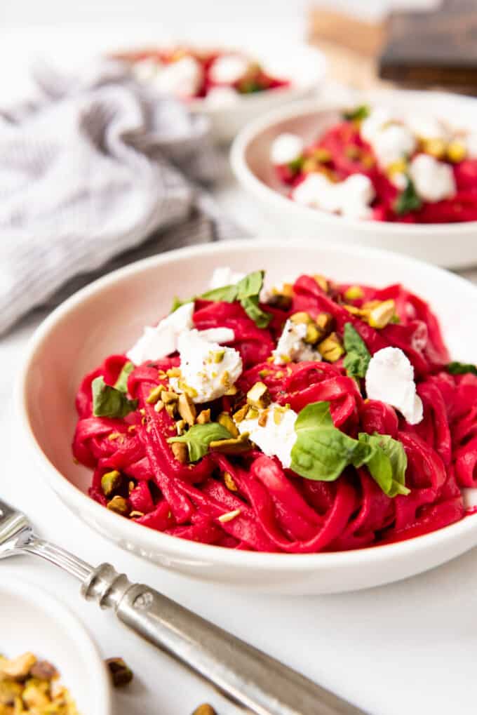 A bowl of cooked fettucine pasta tossed with roasted beet sauce and goat cheese.