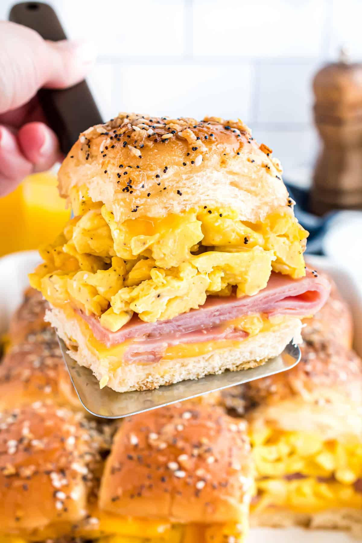 A ham and cheese and egg breakfast slider being lifted on a spatula from the pan.
