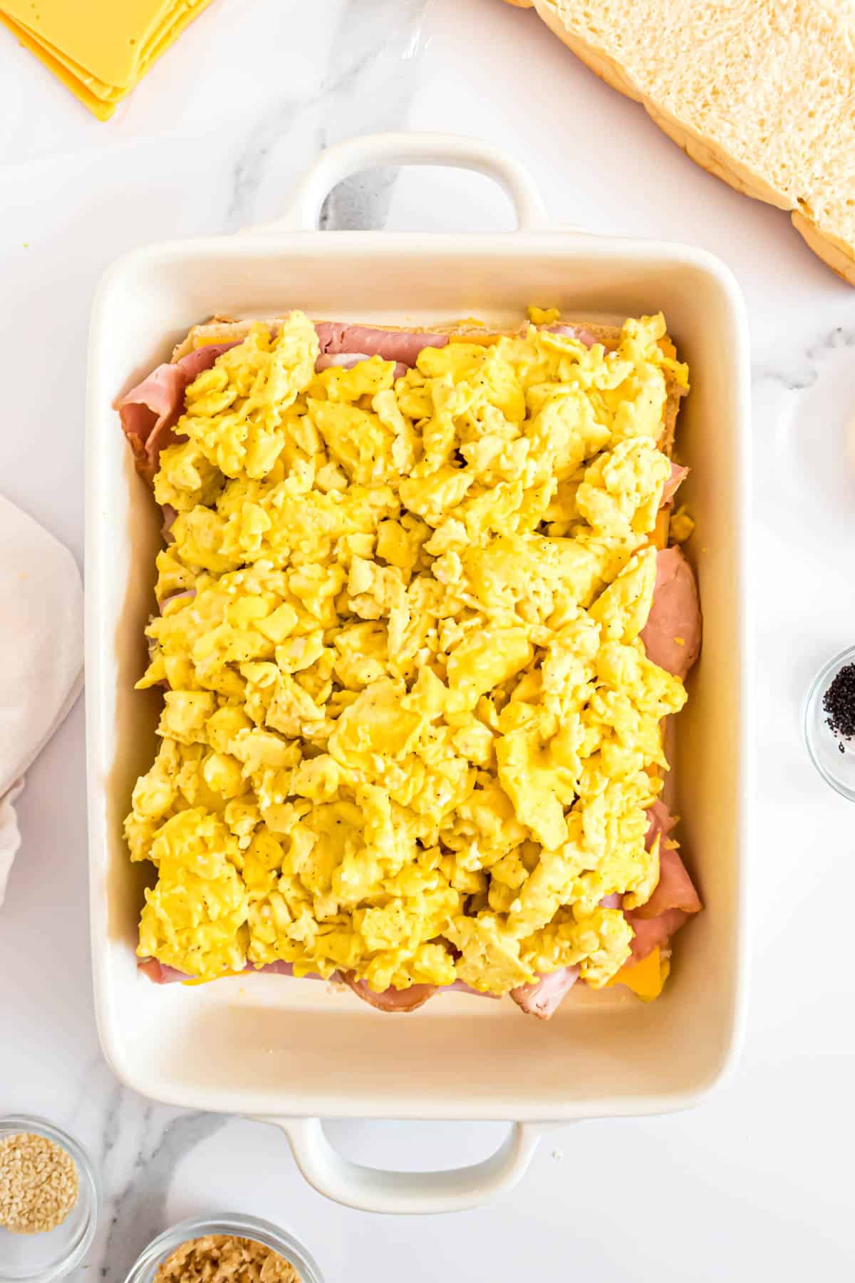 Adding a layer of scrambled eggs on top of ham and cheese for breakfast sliders.