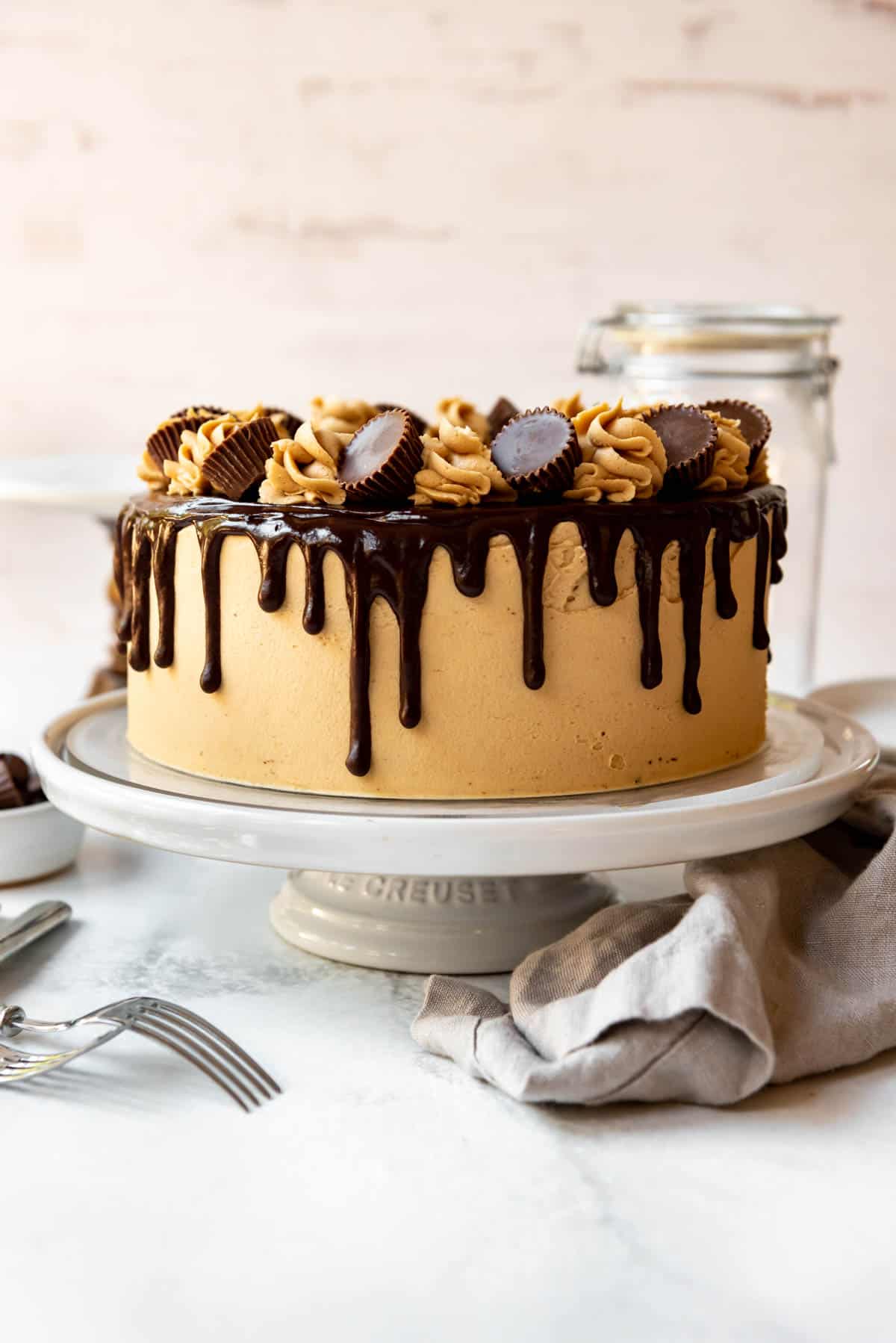 A chocolate peanut butter cake on a white cake stand.