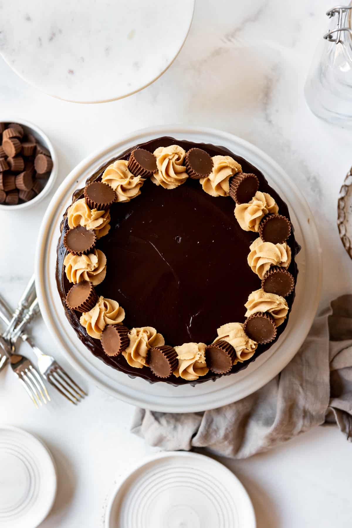 Top view of a Chocolate Peanut Butter Cake with swirls of peanut butter frosting and mini peanut butter cups on top of chocolate ganache.