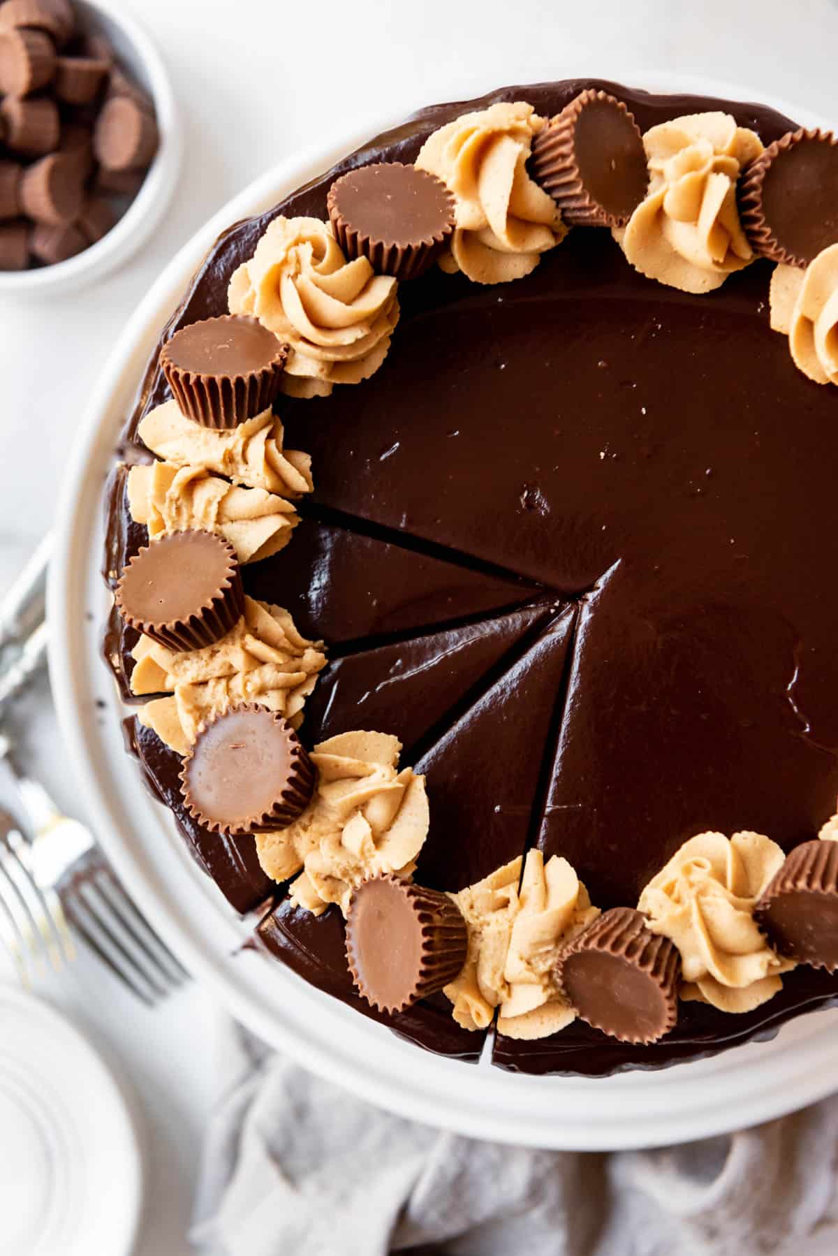 Top view of a Chocolate Peanut Butter Cake with swirls of peanut butter frosting and mini peanut butter cups on top of chocolate ganache.