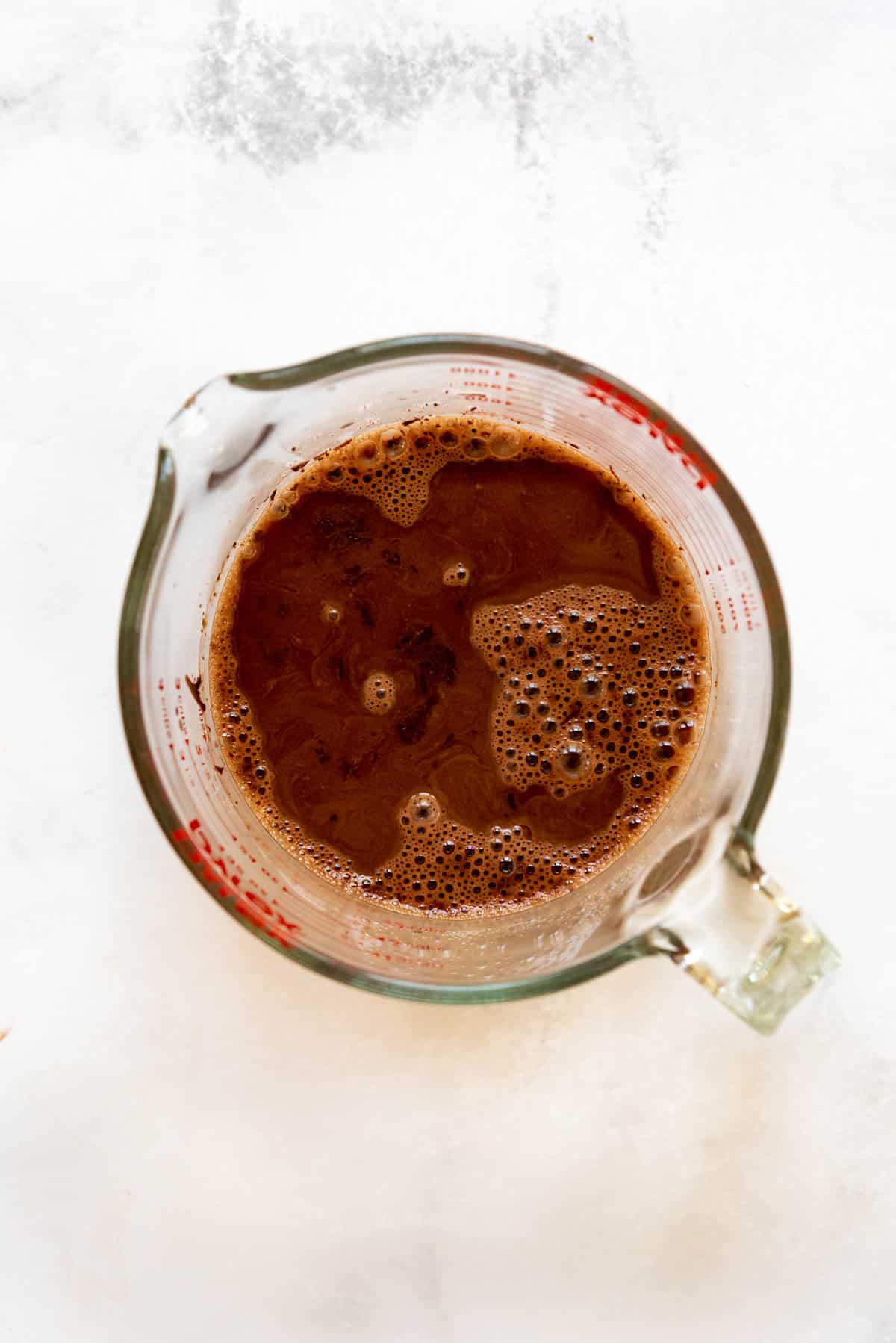 Top view of a glass measuring jug with a cocoa powder mixture in it.