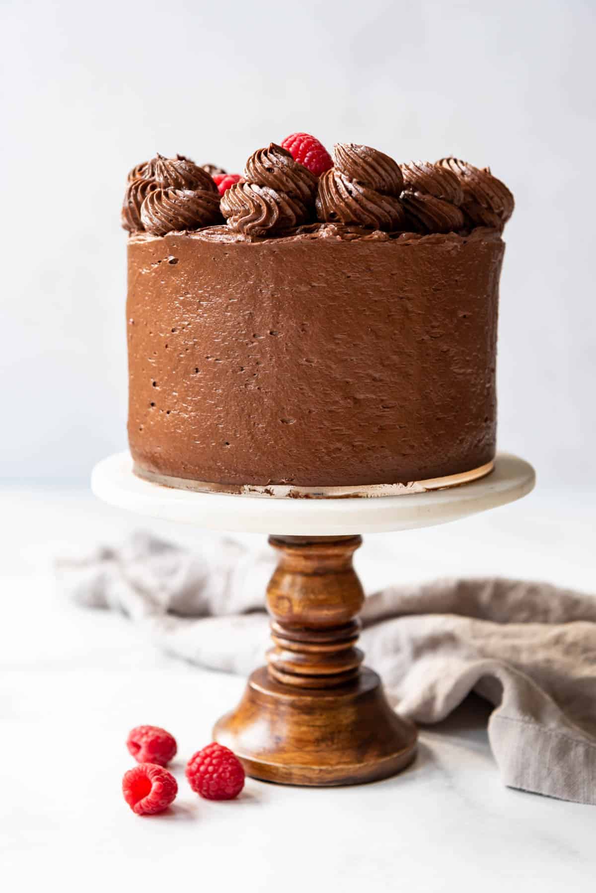 A finished raspberry chocolate cake on a cake stand.