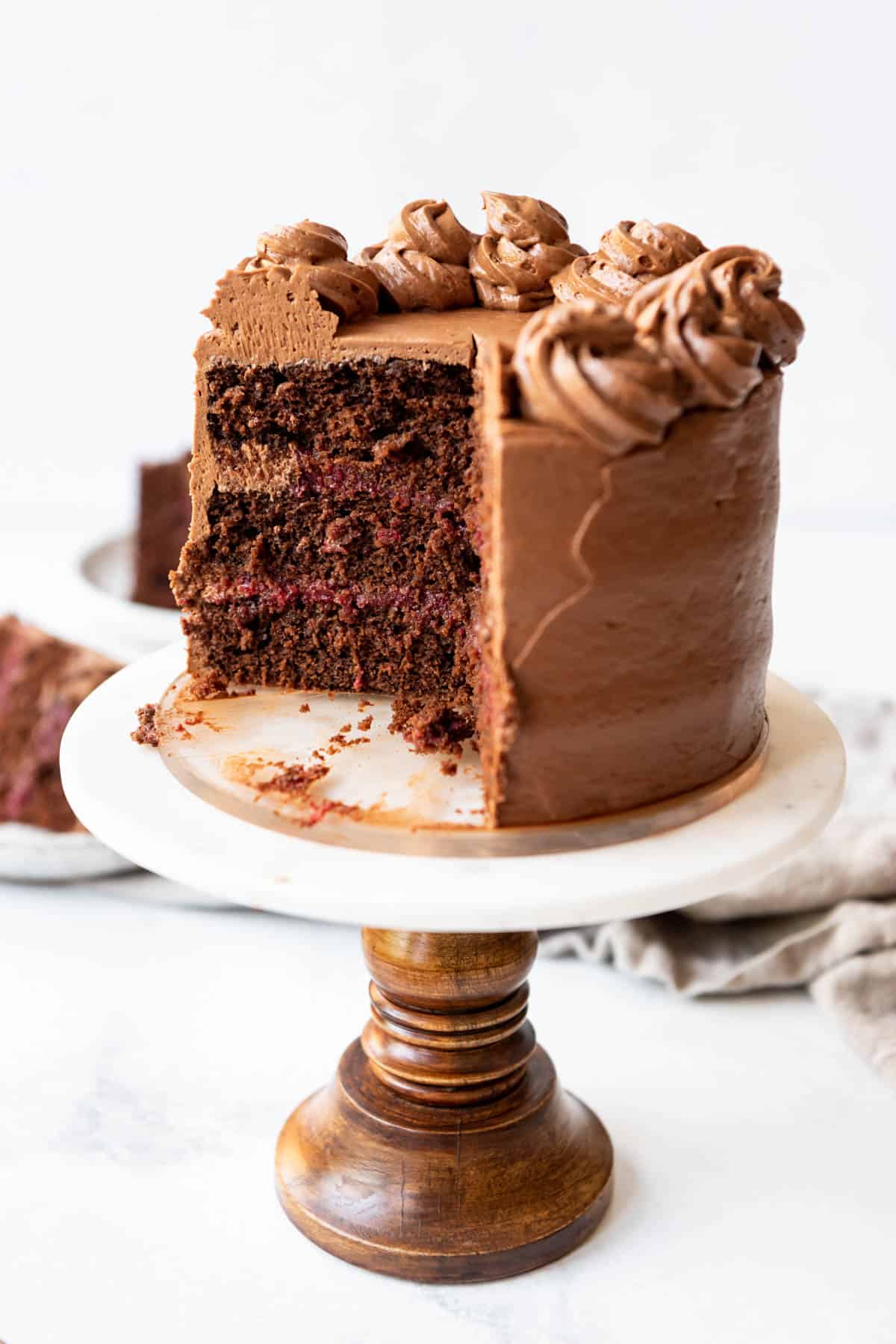 A sliced chocolate raspberry cake on a cake stand.