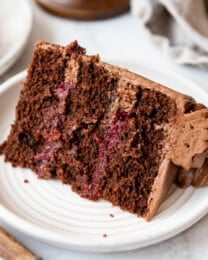 A slice of raspberry chocolate cake on a white plate.