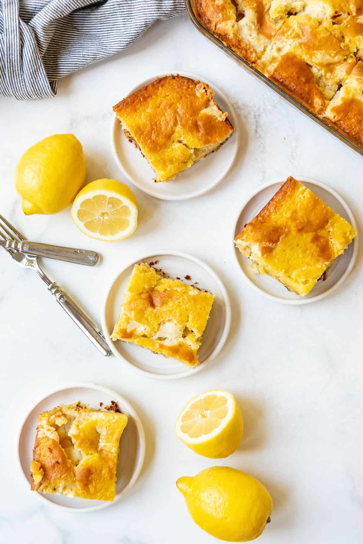 An overhead image of slices of lemon earthquake cake next to fresh lemons.