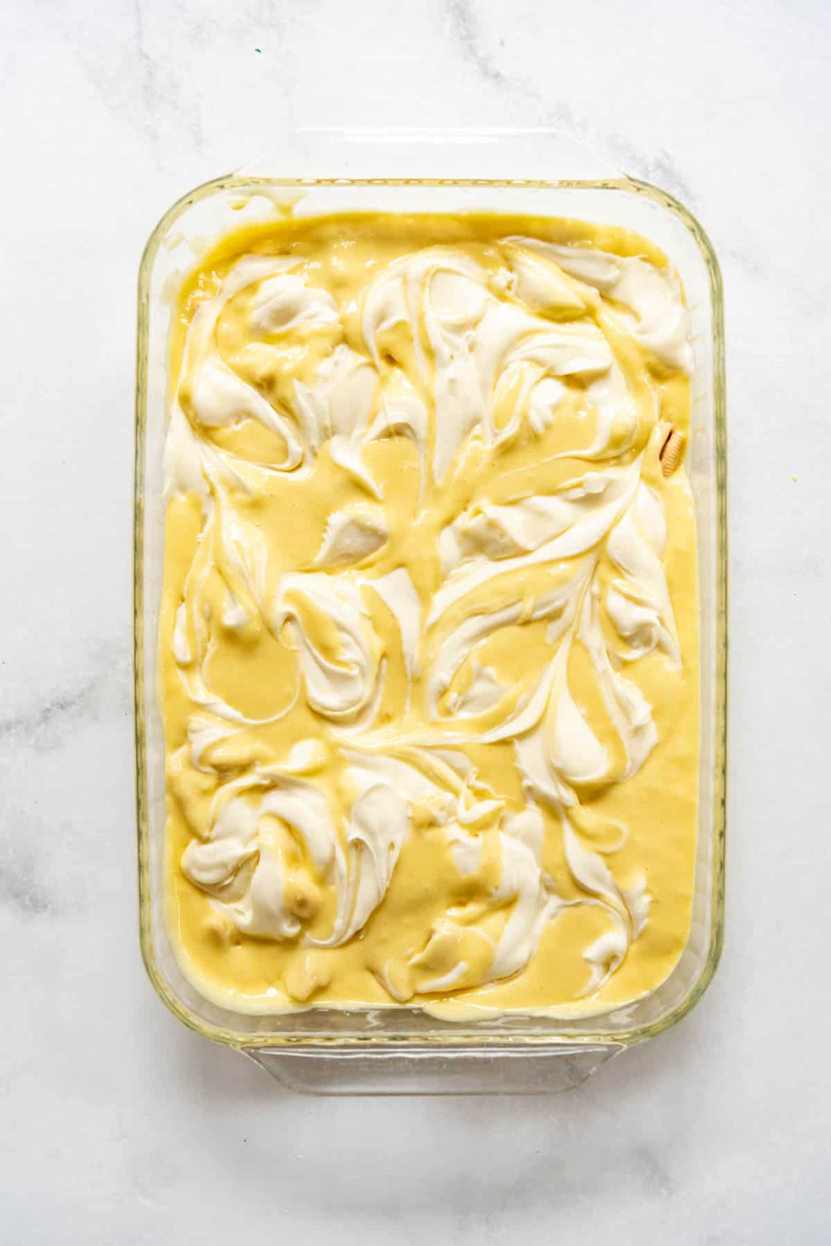 Cream cheese frosting swirled into cake batter in a 9x13-inch pan.