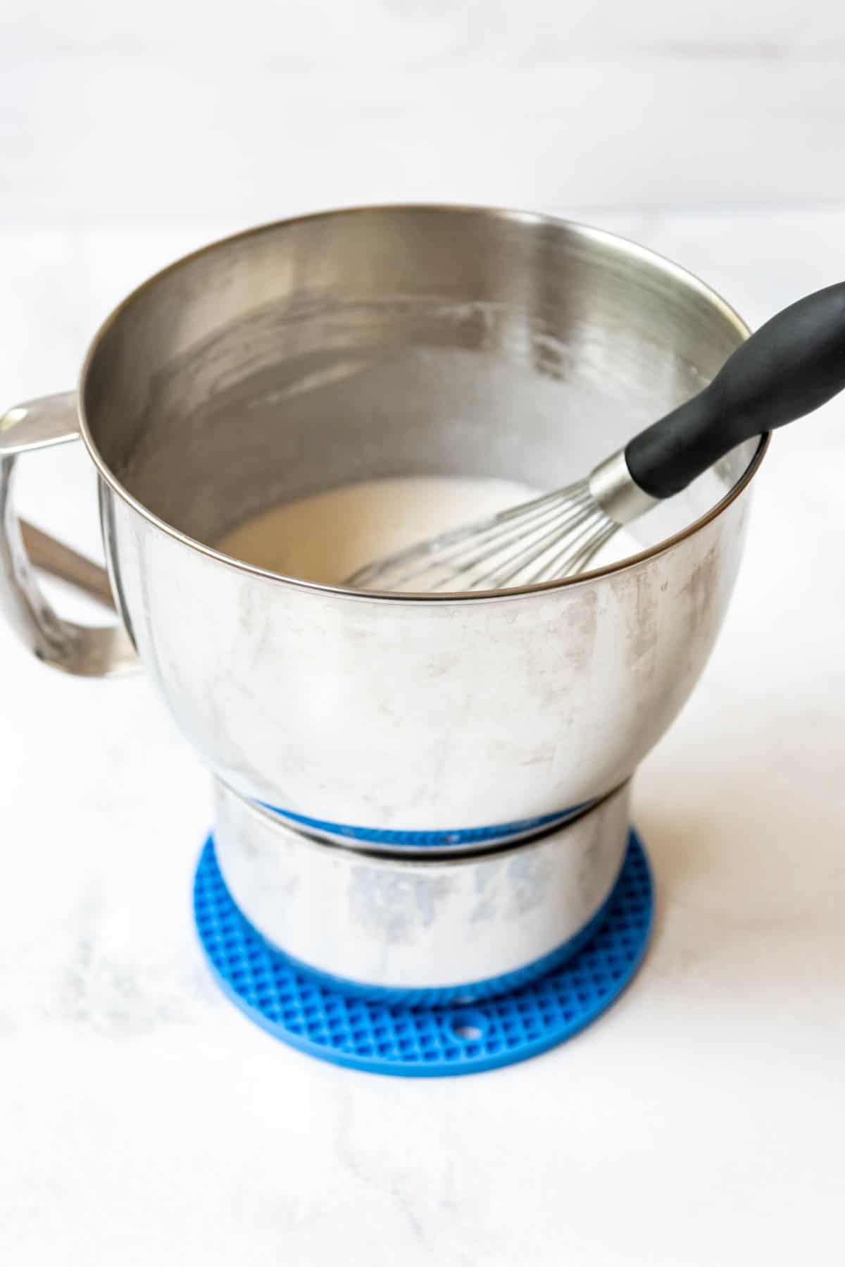 A bain marie made with a saucepan and a metal mixing bowl with egg whites and sugar.