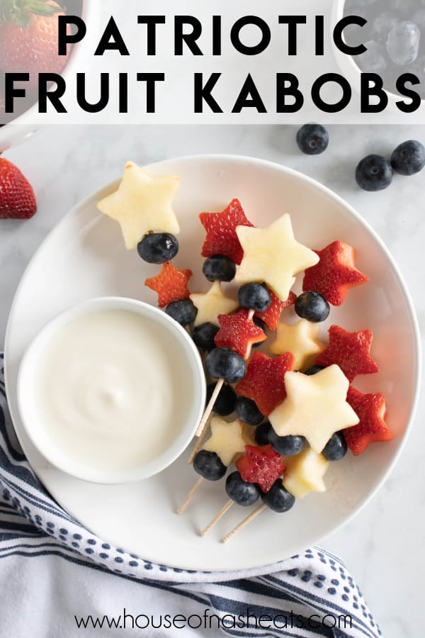 4th of July fruit kabobs on a plate with a bowl of yogurt dip.