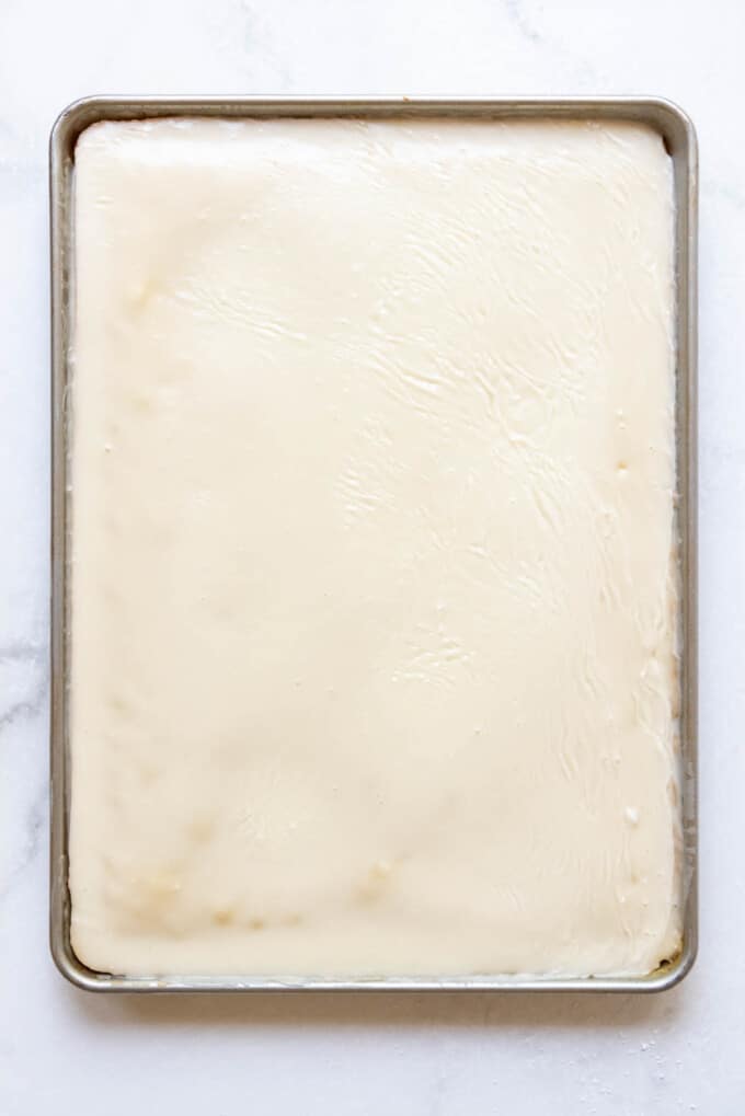 A glazed white Texas sheet cake in a large half baking sheet.