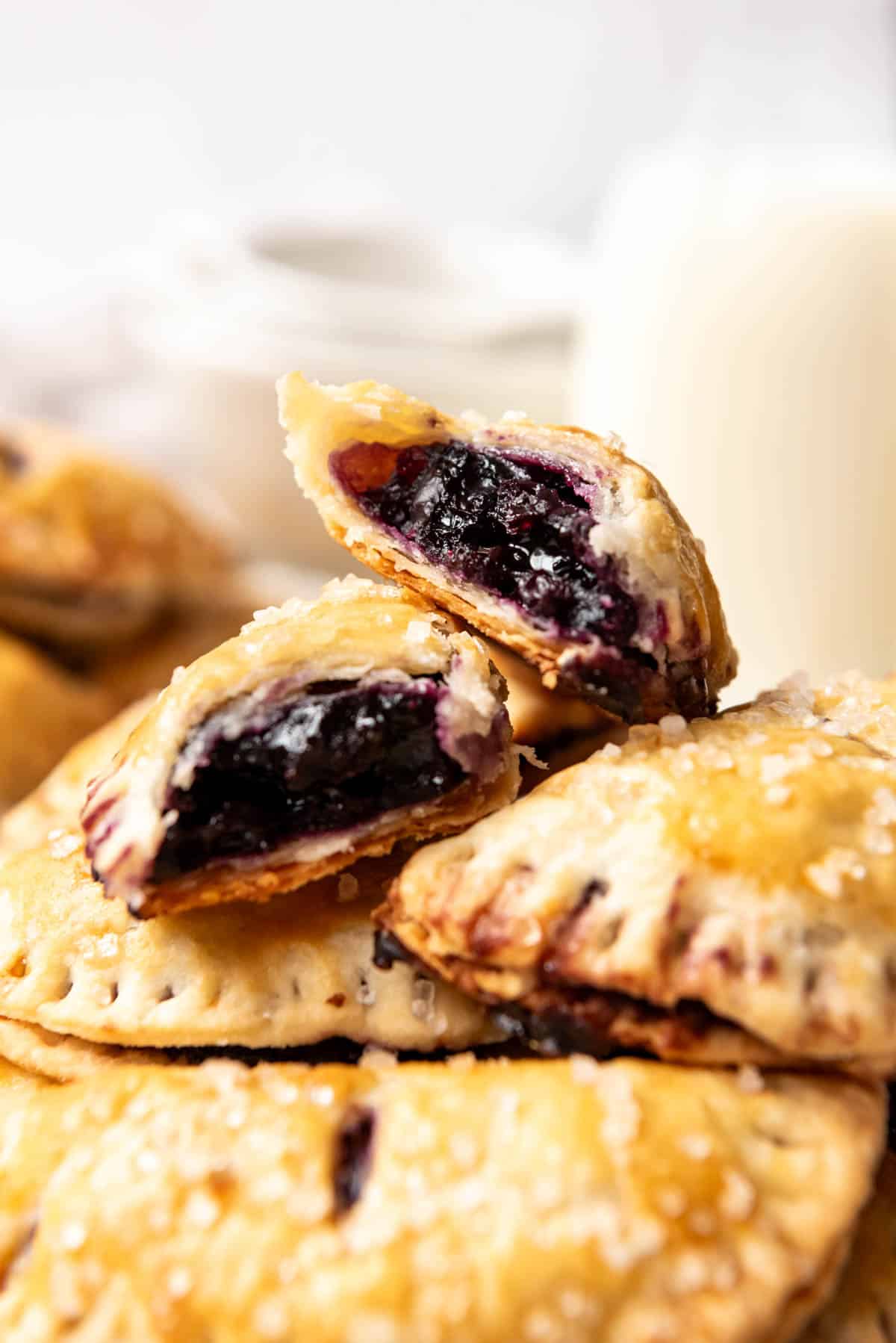 Stacked blueberry hand pies with the top one broken in half to show the filling.