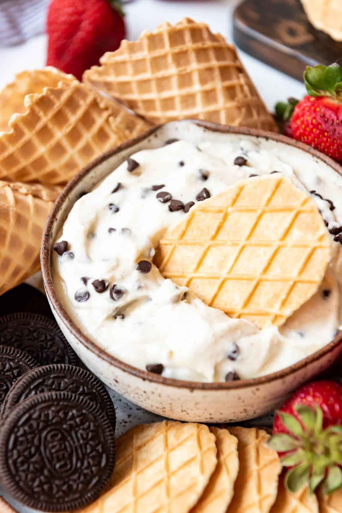 Close up of cannoli dip in a bowl surrounded by sweet treats to dip.