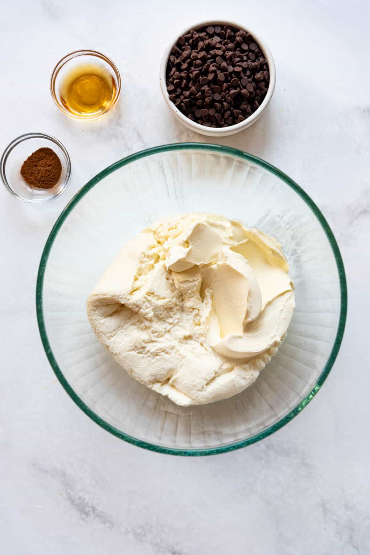 Combining ricotta cheese and mascarpone cheese in a large glass mixing bowl.