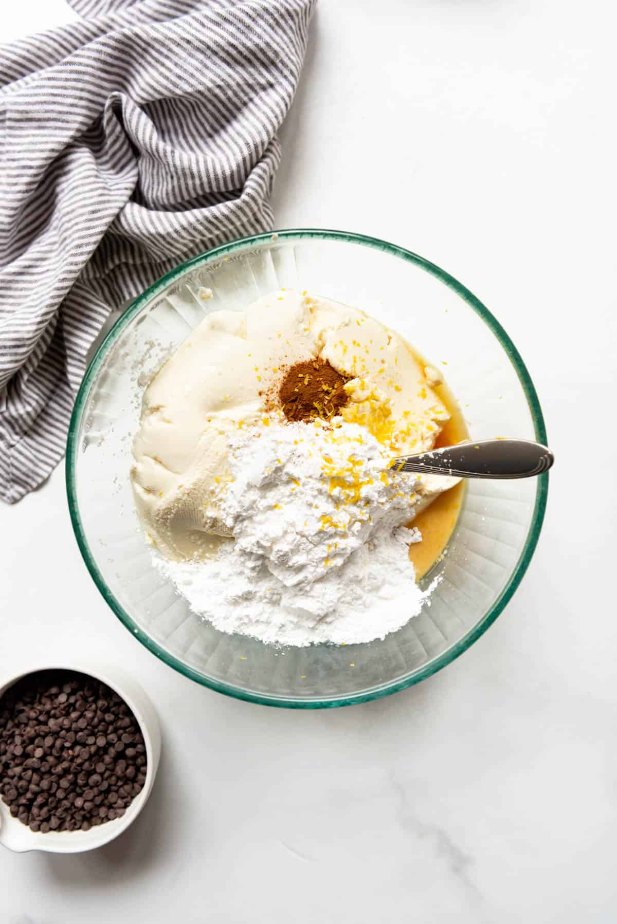 Combining ricotta cheese in a bowl with powdered sugar, cinnamon, lemon zest, and vanilla extract to make cannoli filling.