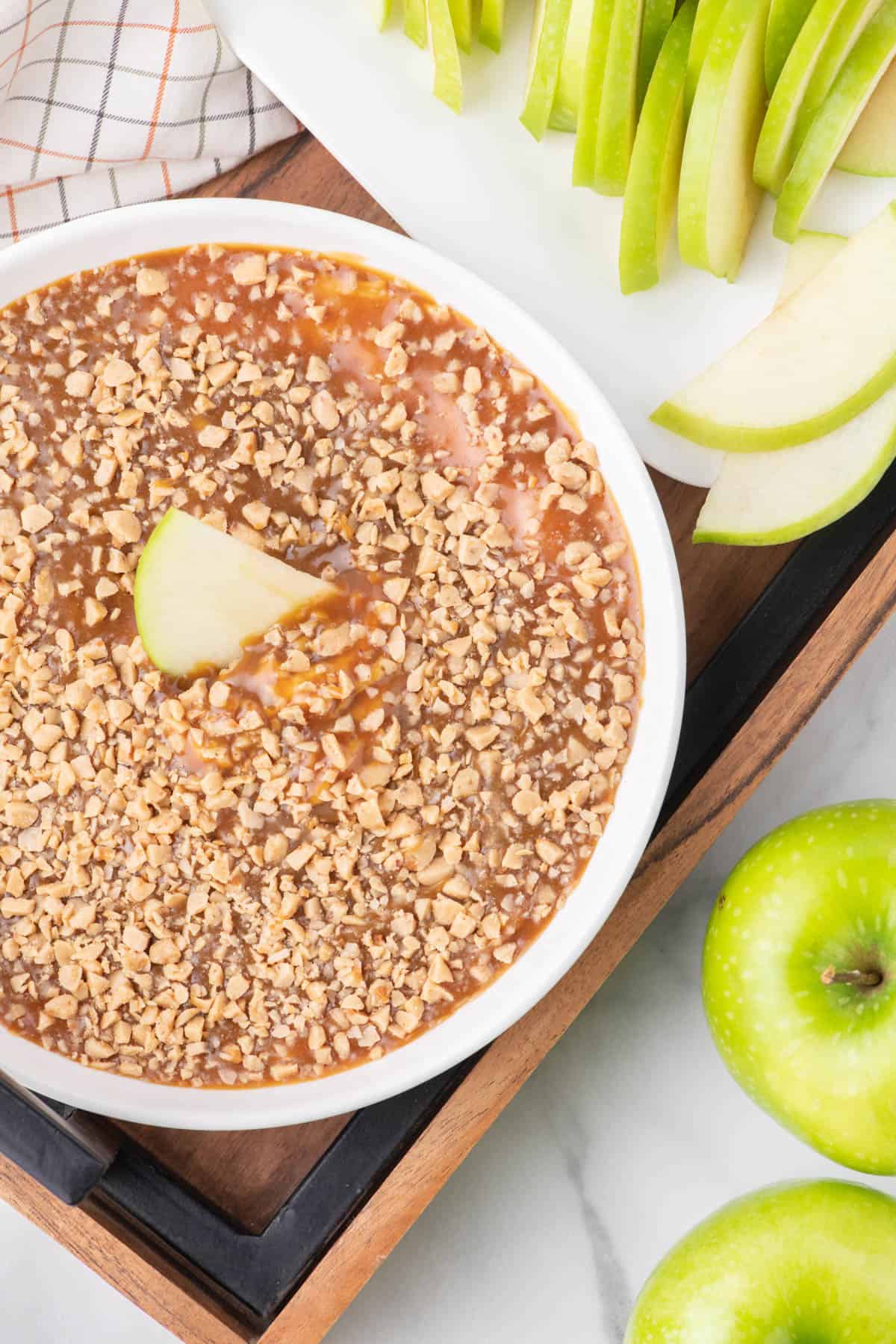 Top view of caramel apple dip in a white serving dish with apple slices in the top.