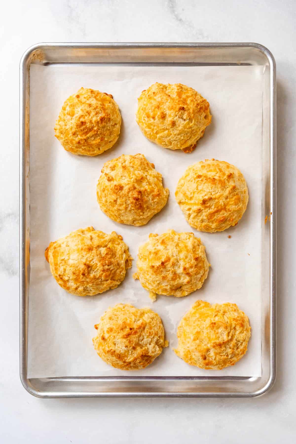 Baked cheddar bay biscuits on a baking sheet.