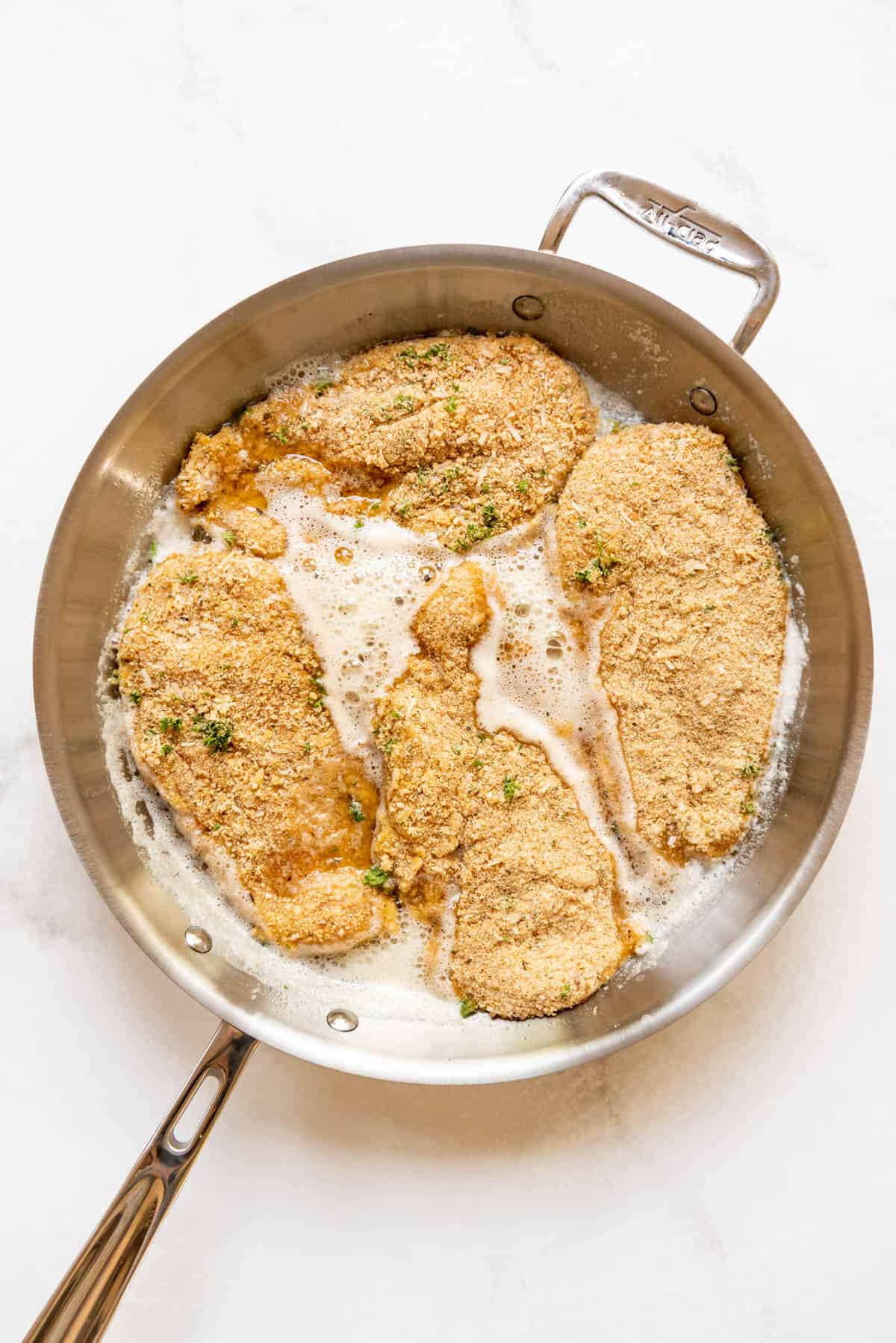 Pan frying breaded chicken breasts for chicken parmesan.
