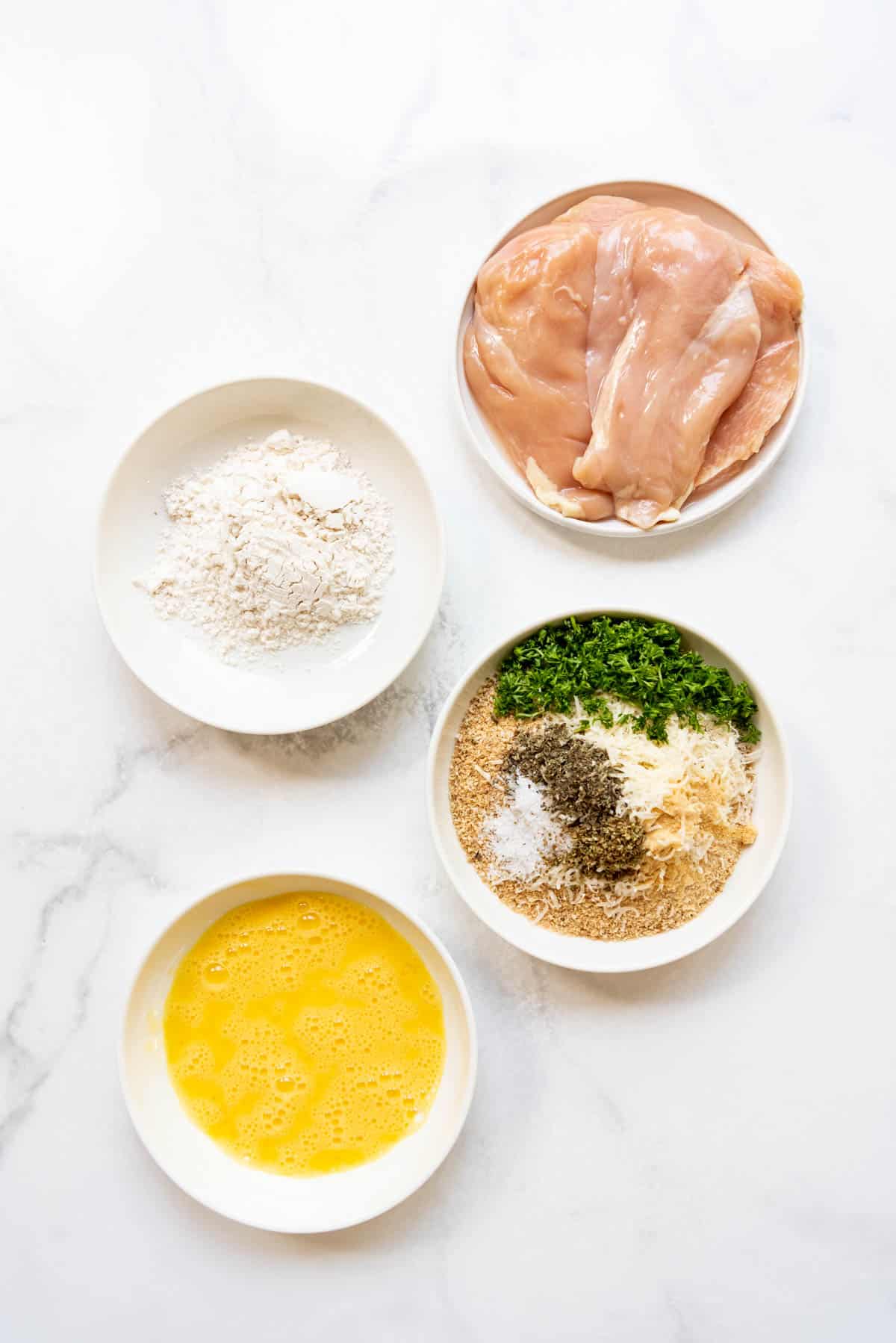 Creating dipping stations for dredging seasoned chicken breasts in flour, beaten eggs, and seasoned breadcrumbs to make chicken parm.