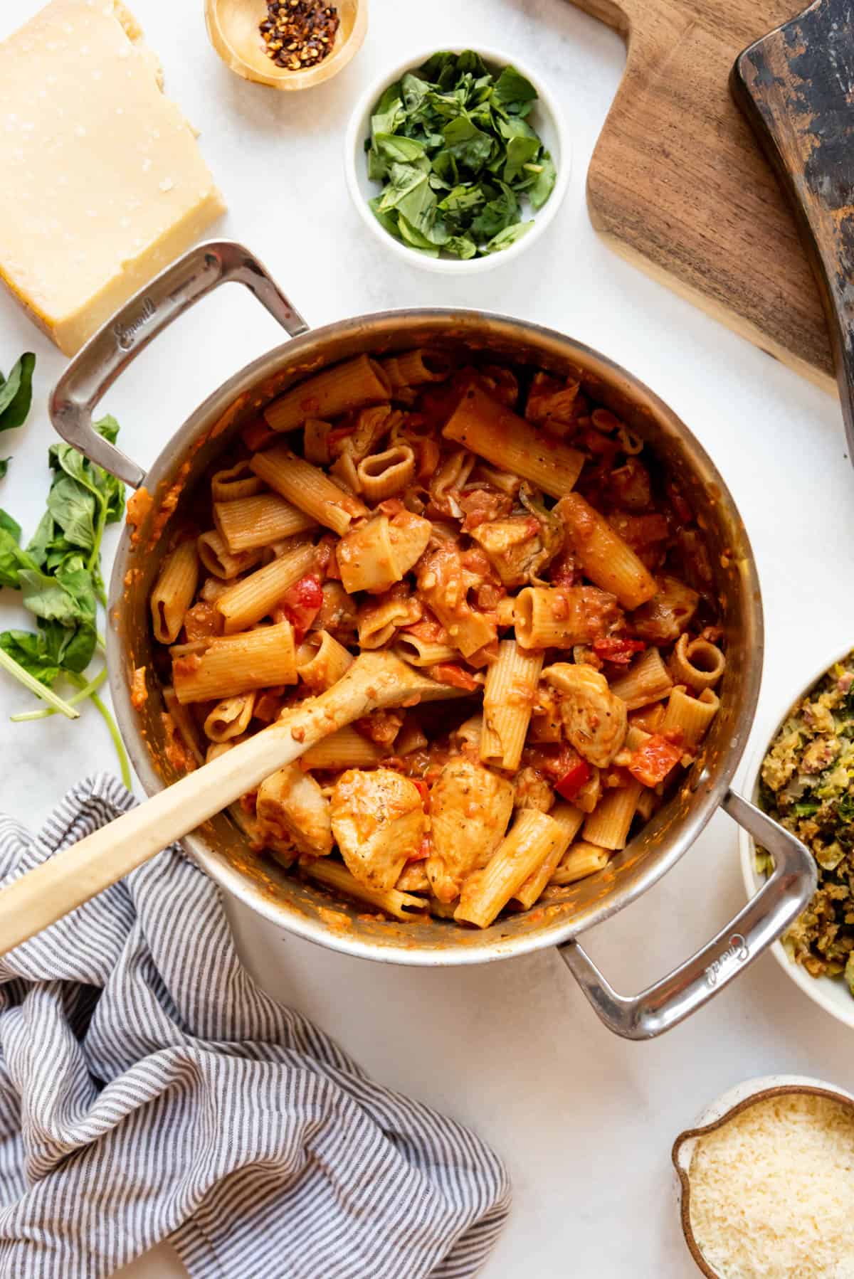 A large pot of chicken riggies with a wooden spoon in it.