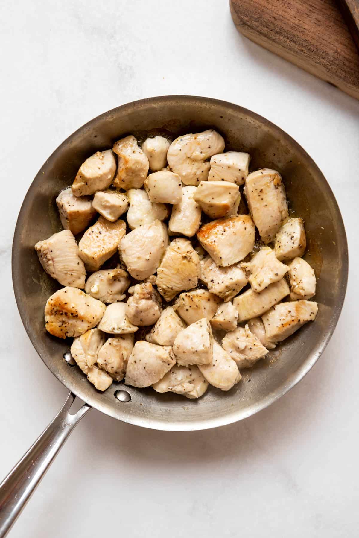 Seared chunks of chicken in a large pan.