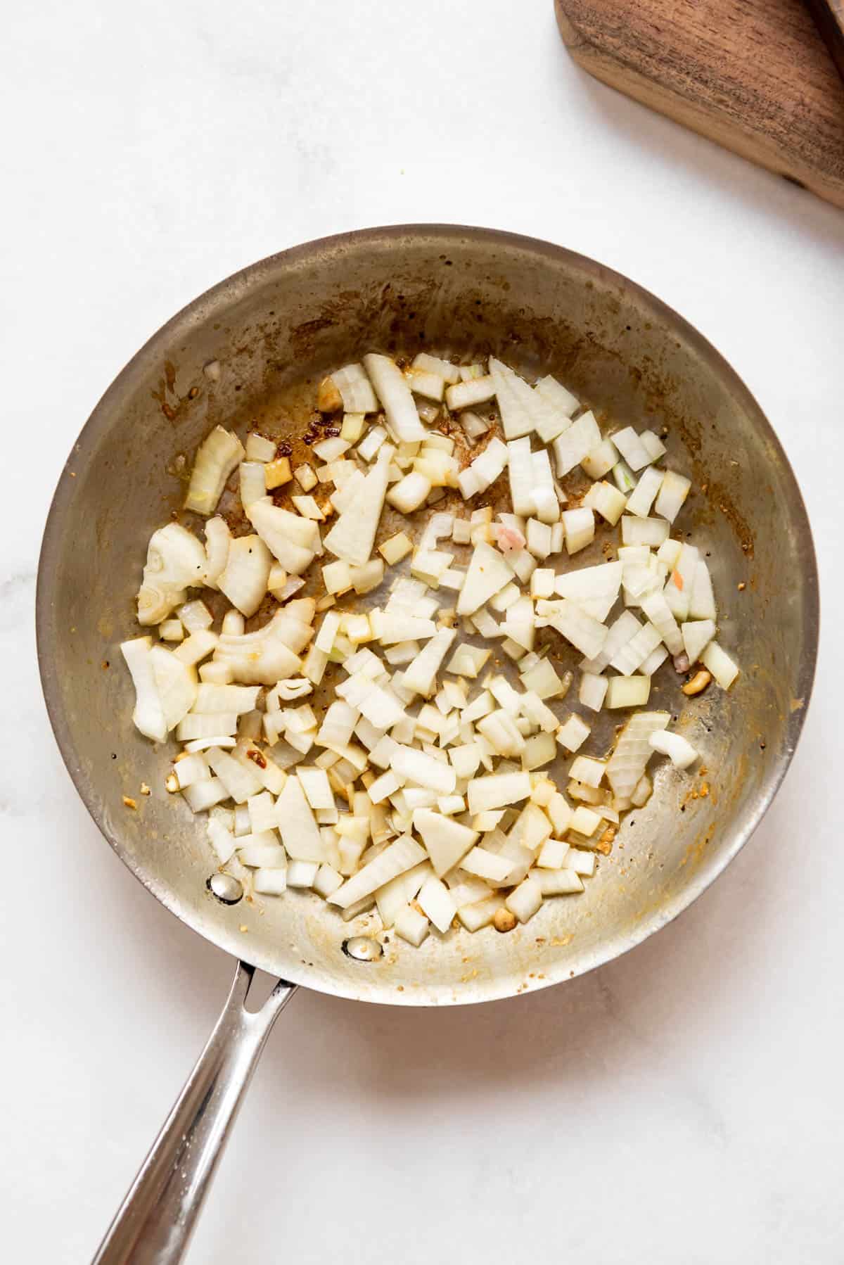 Sauteing chopped onions and garlic in a large pan.