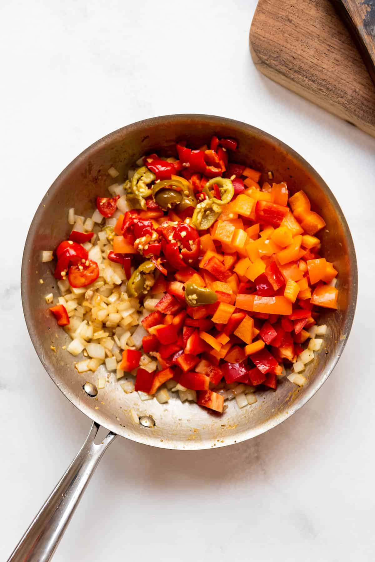 Adding chopped vegetables to a large skillet.