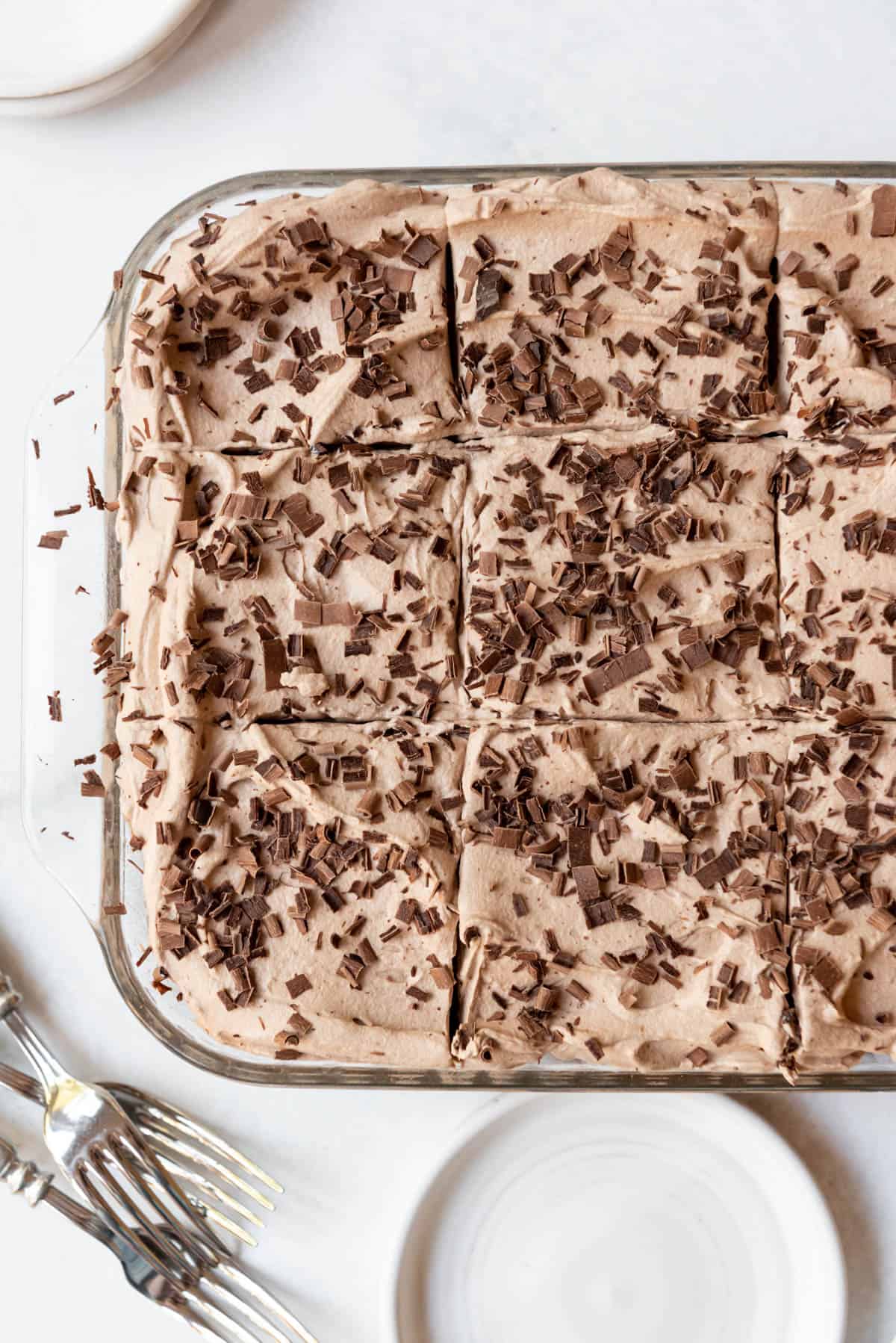 An overhead image of chocolate tres leches cake cut into squares.