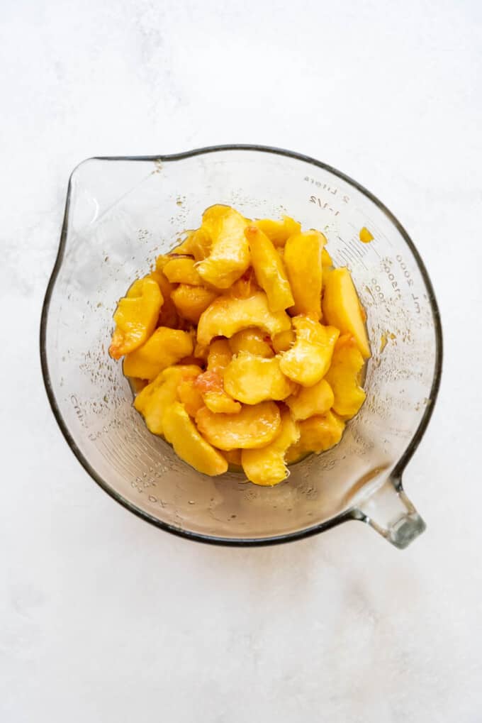 Sliced peaches in a glass mixing bowl.