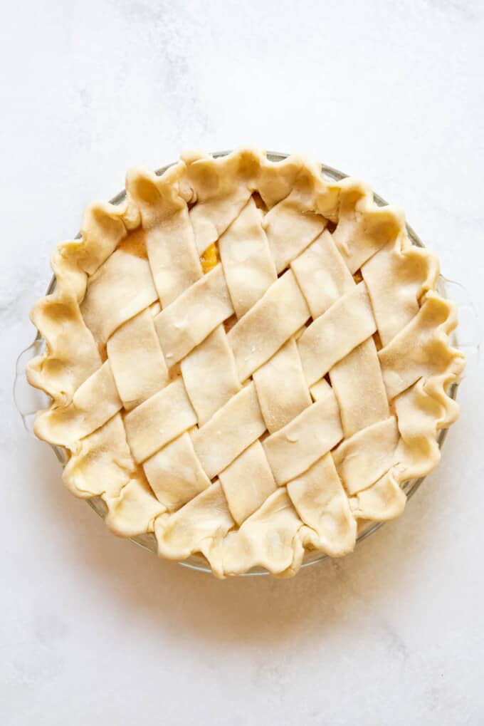 An unbaked peach pie with a lattice pie crust.