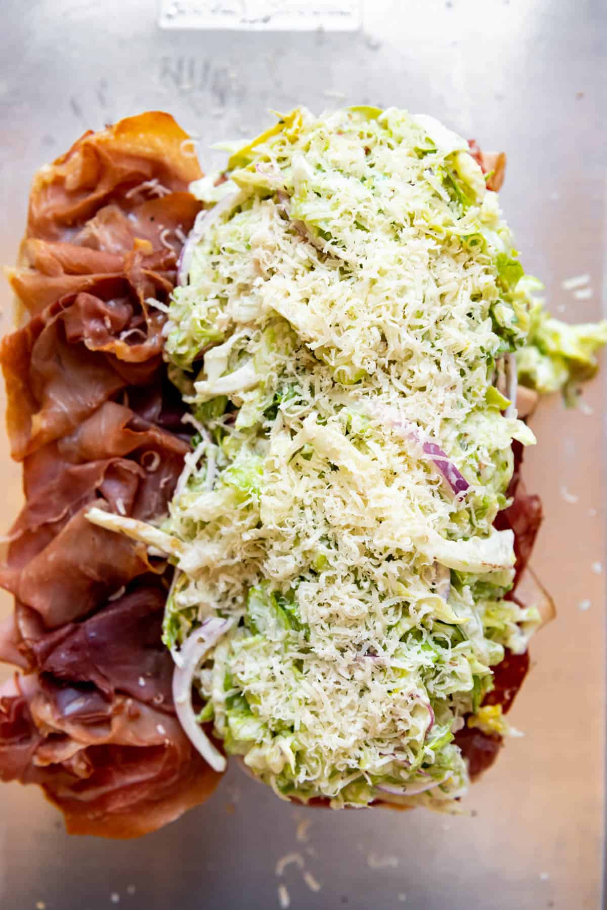 Piled grinder salad with freshly grated parmesan cheese on an Italian grinder sandwich.