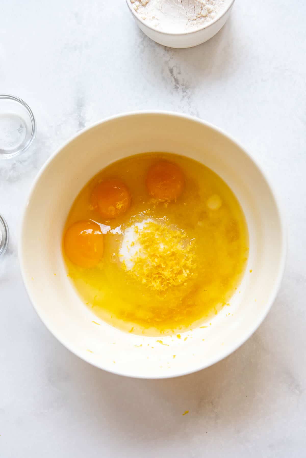 Combining granulated sugar, eggs, lemon juice, lemon zest, and melted butter in a large mixing bowl.