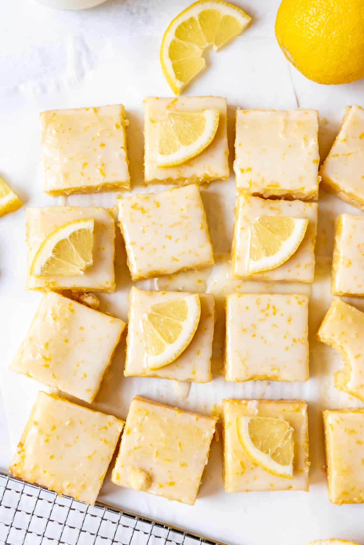 Glazed lemon blondie squares with thin lemon wedges decorating the tops of some of them.