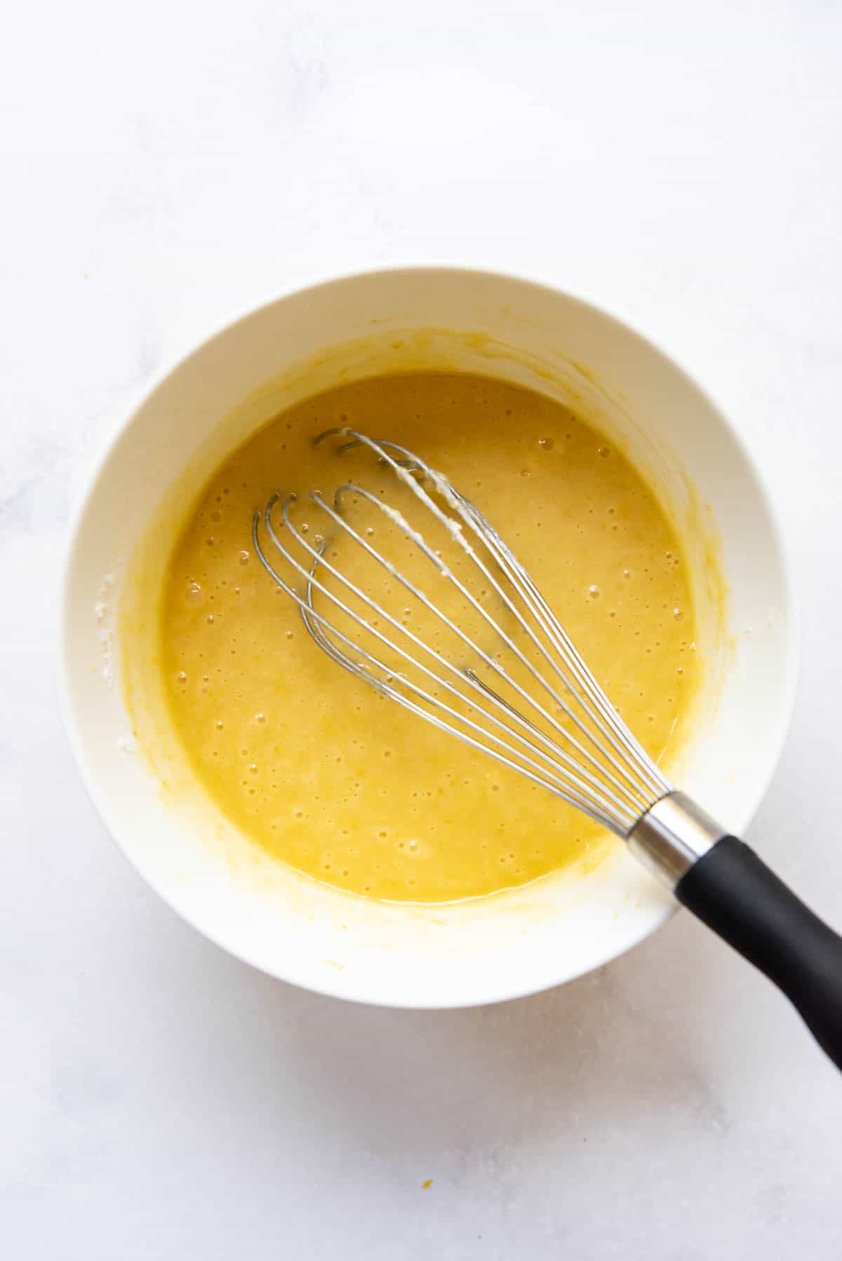 Lemon brownie batter in a mixing bowl with a whisk.