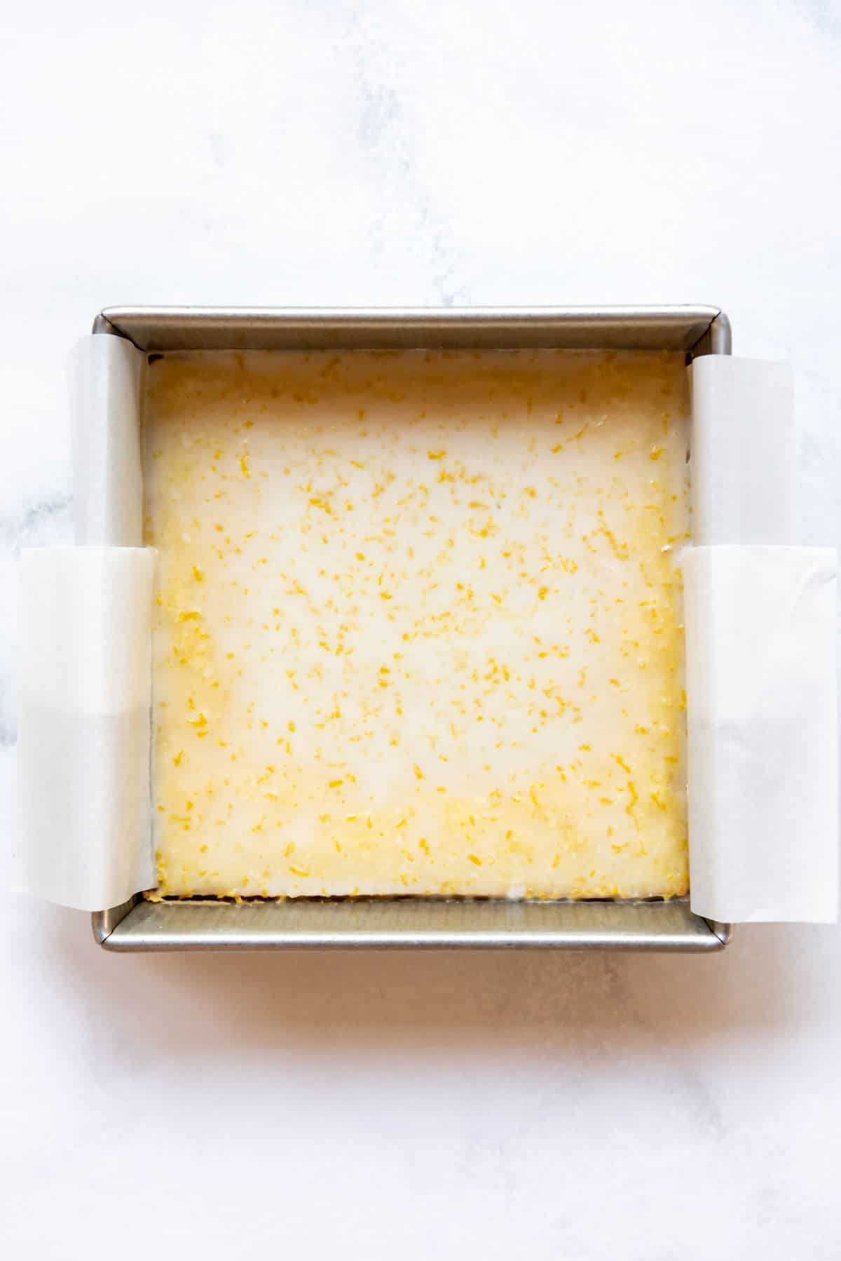 Adding a simple lemon glaze to lemon brownies in a square pan.