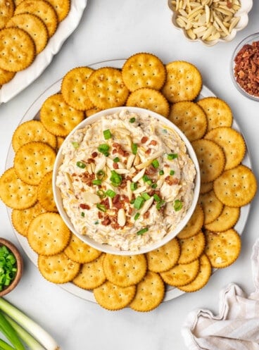 Million dollar dip in a bowl surrounded by Ritz crackers for serving.