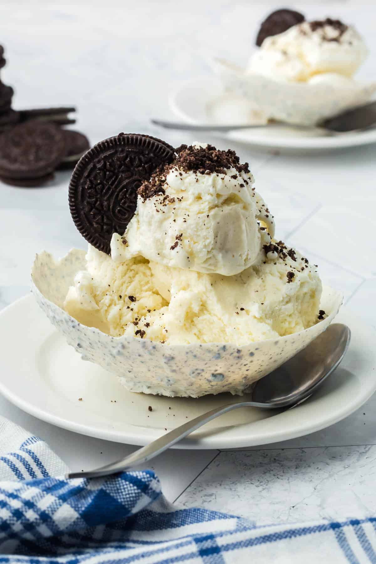 An Oreo balloon bowl filled with ice cream and crushed Oreo cookies on a plate with a spoon.