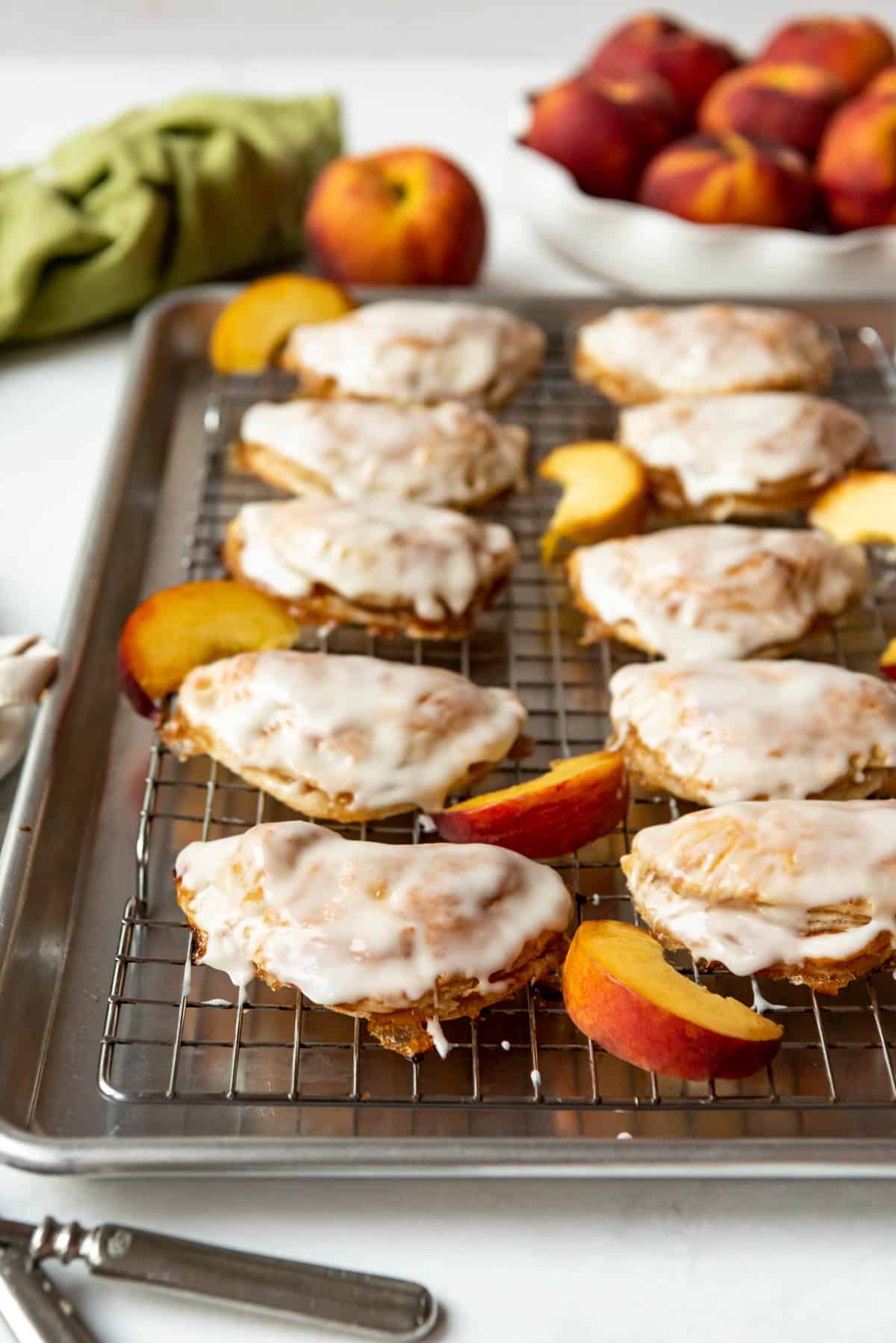 Homemade peach hand pies with vanilla glaze on a wire rack over a baking sheet.
