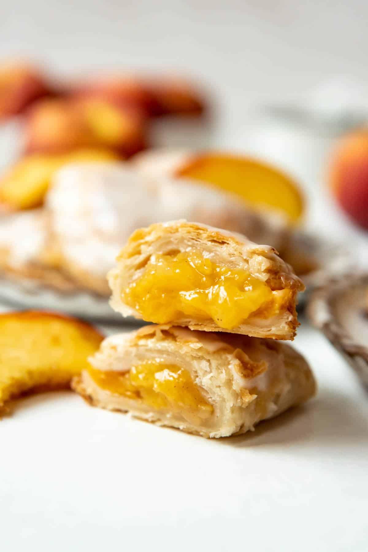 A peach hand pie that has been cut in half with the halves stacked on top of each other showing the peach filling inside.
