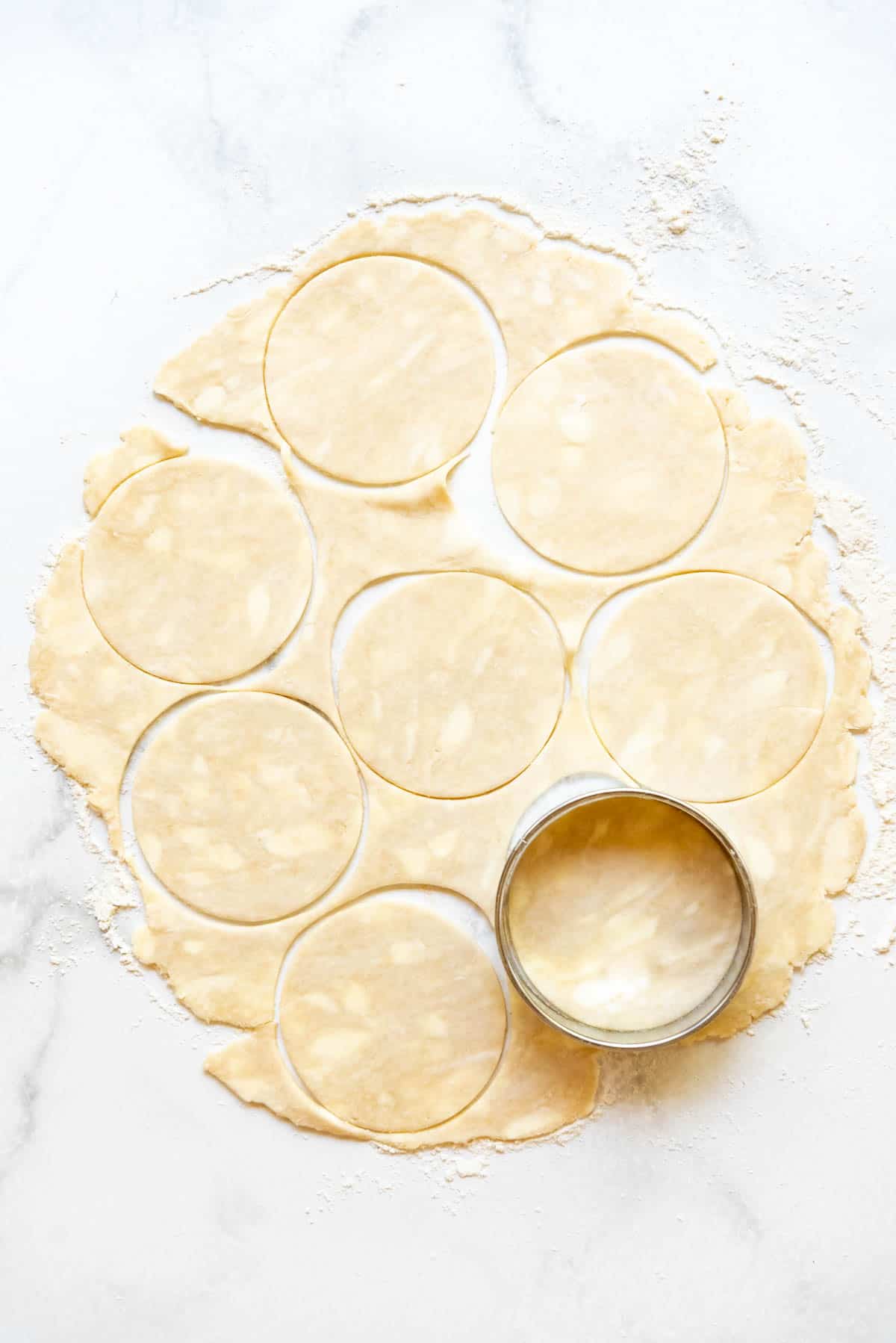Cutting out circles of pie dough with a large round cutter.