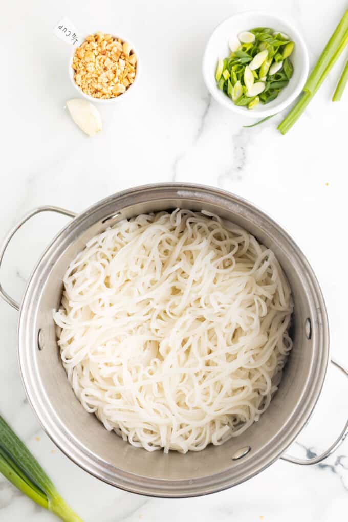 Top view of a cooking pot with cooked rice noodles in it.