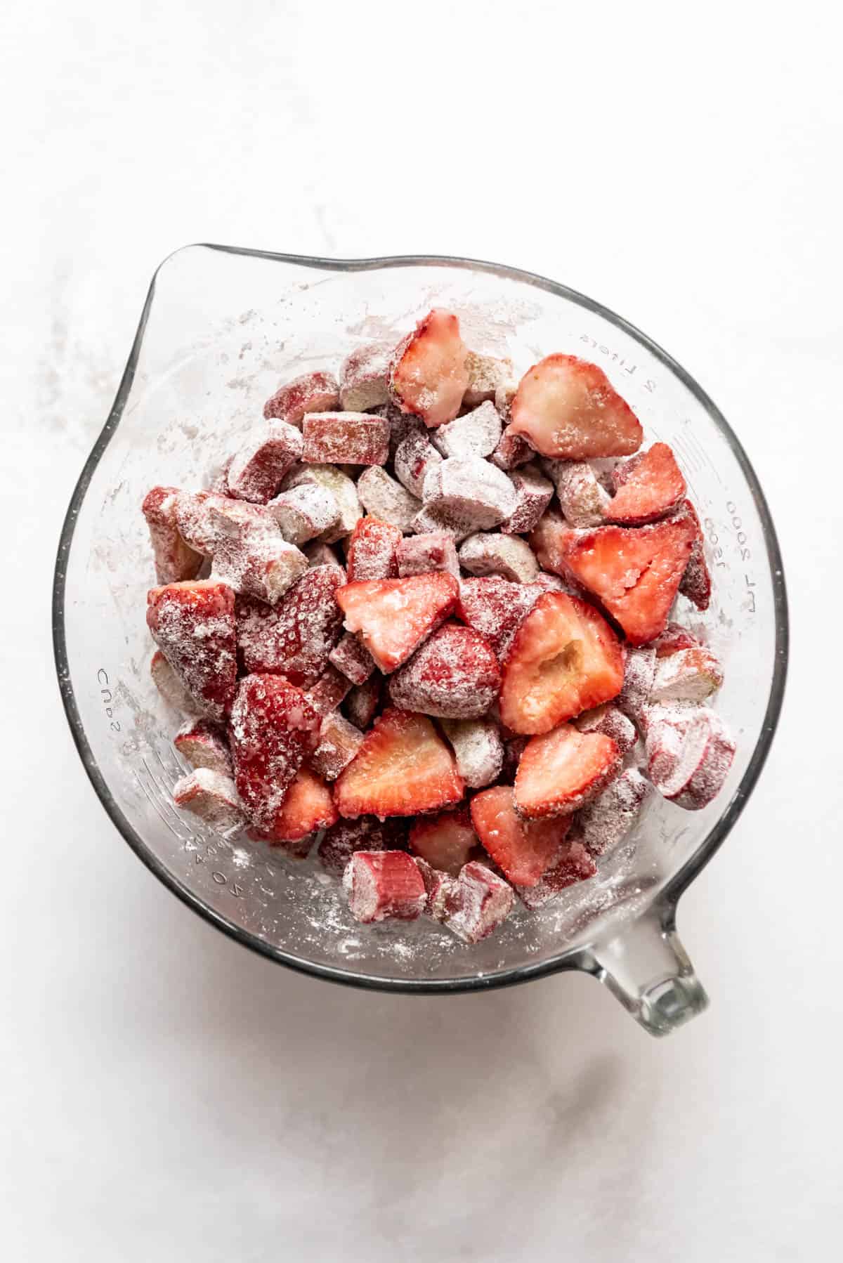 Combining sliced strawberries and rhubarb with sugar, cornstarch, and lemon juice in a large bowl.