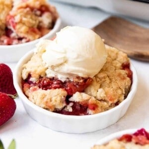 An image of a bowl of strawberry rhubarb cobbler with vanilla ice cream on top.