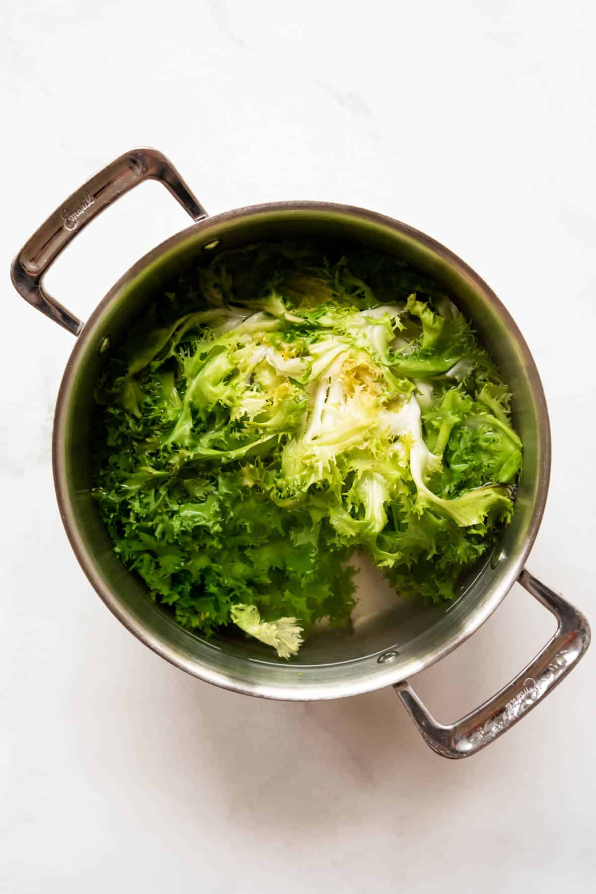 Blanching escarole in a large pot of boiling water.