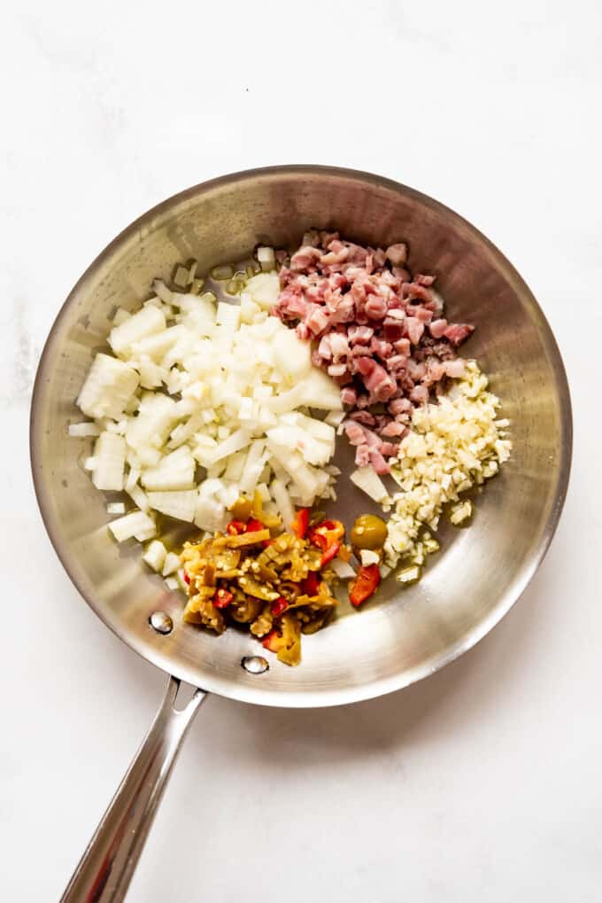 Chopped onions, pickled cherry peppers, pancetta, and garlic in a skillet.