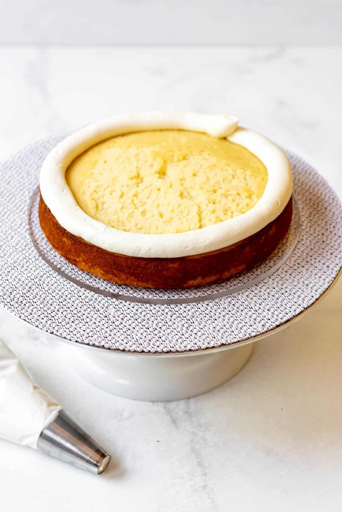 A ring of white chocolate frosting piped around the top of a layer of cake.