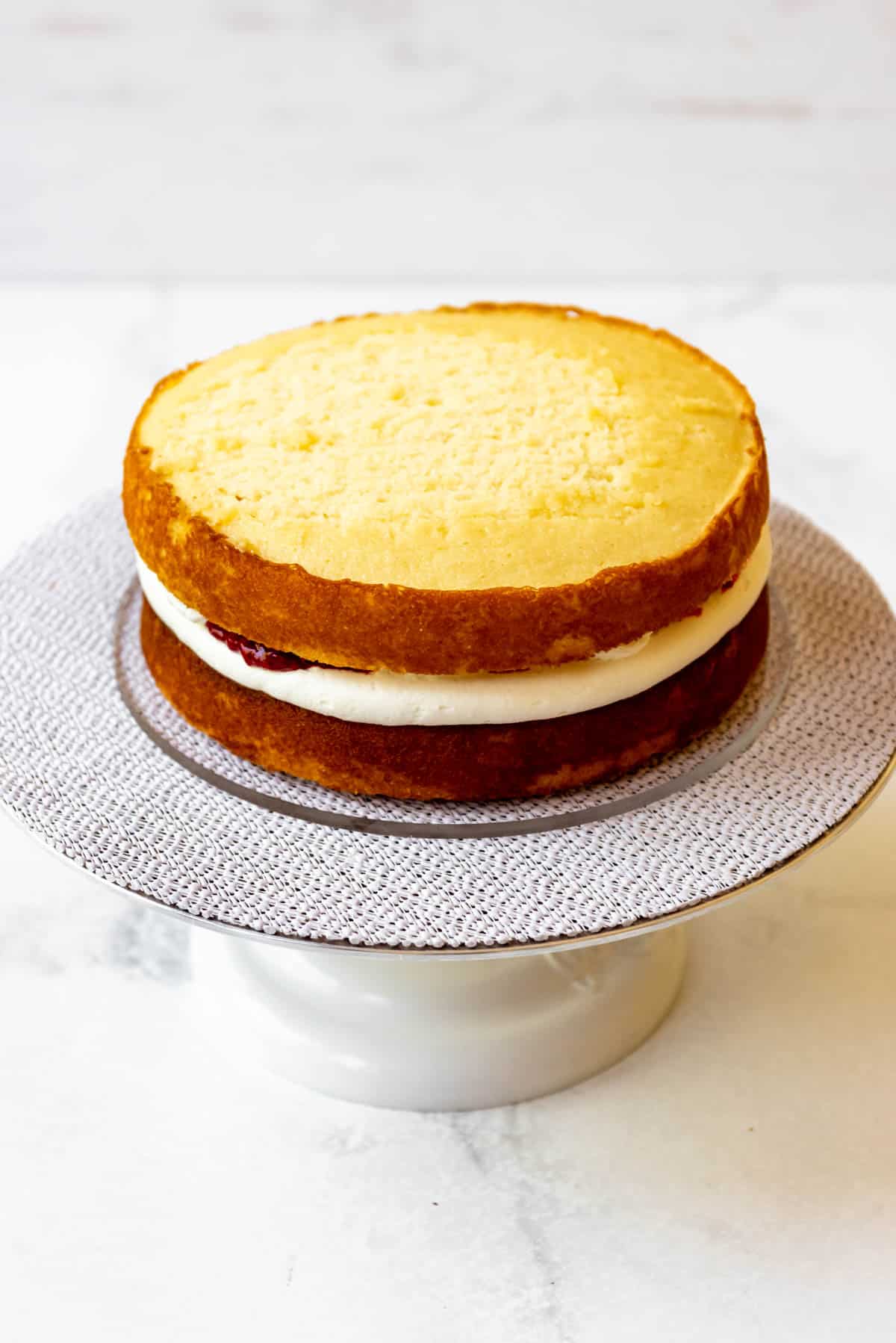 Adding another layer of cake to a white chocolate raspberry layer cake.