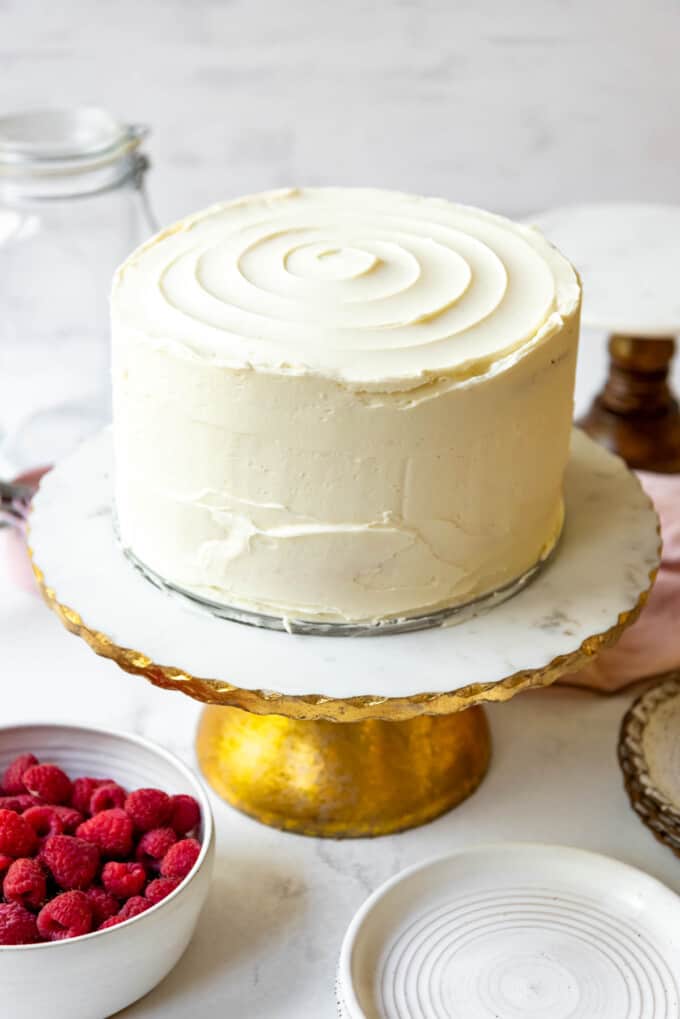 A whole frosted white chocolate raspberry cake without decorations on top.