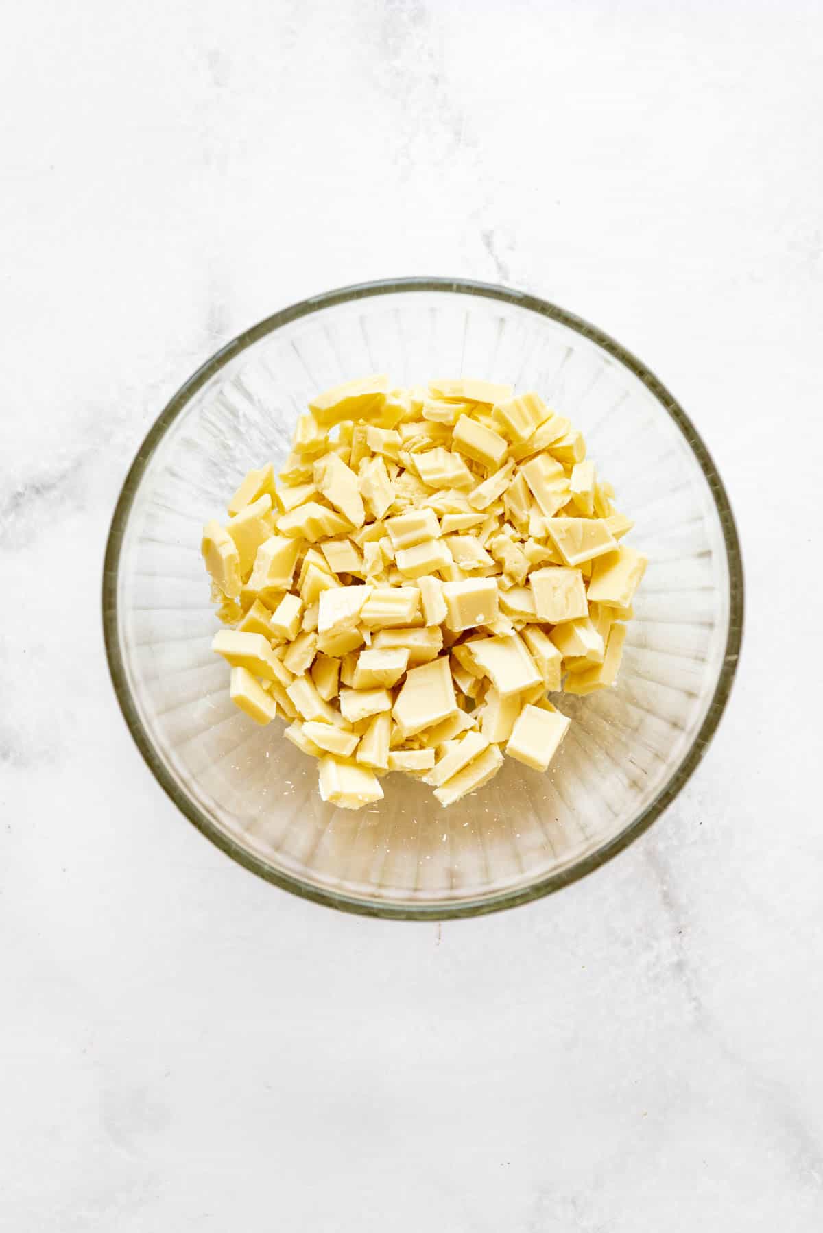 Chopped white chocolate in a glass bowl.